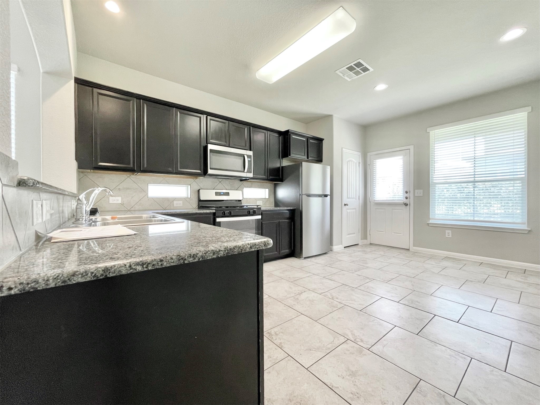 407 Rhetoric Way Pflugerville, TX 78660 - Photo 11 of 38 a kitchen with kitchen island granite countertop a sink window and refrigerator
