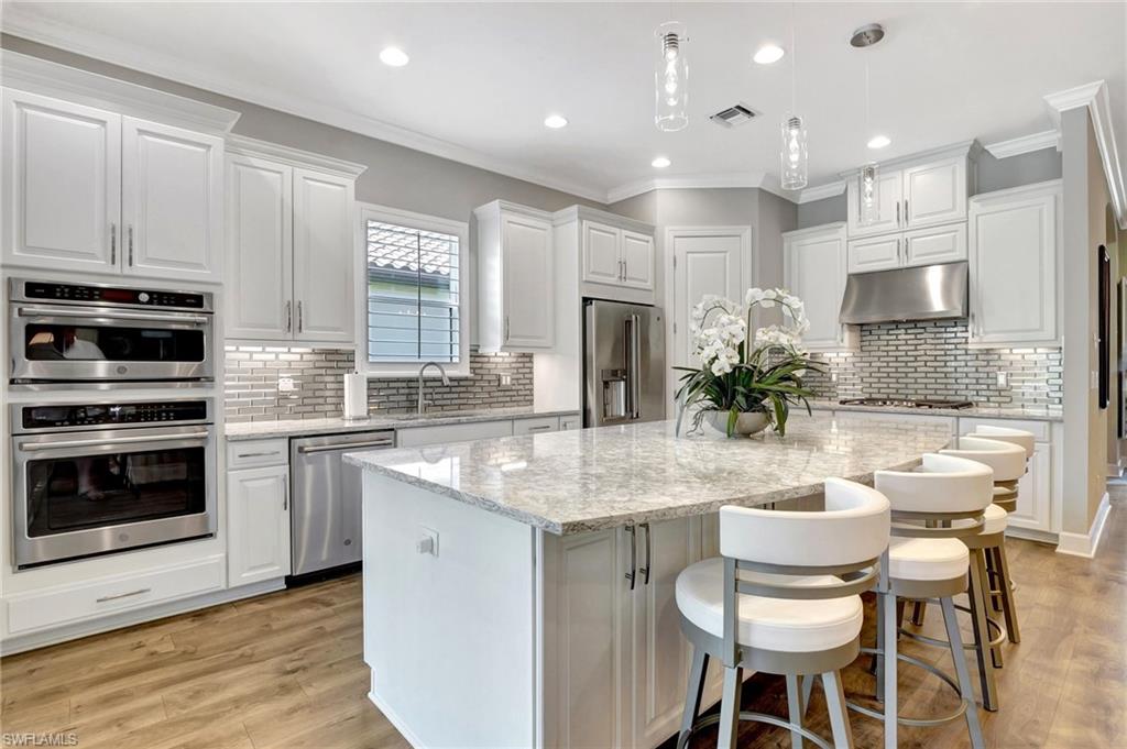 8558 Maggiore Court Naples, FL 34114 - Photo 16 of 50 a kitchen with kitchen island granite countertop a white cabinets and chairs