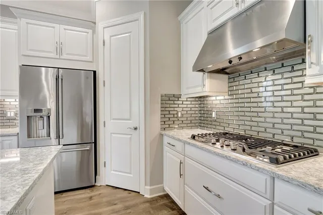 a kitchen with stainless steel appliances granite countertop sink a refrigerator and wooden floor