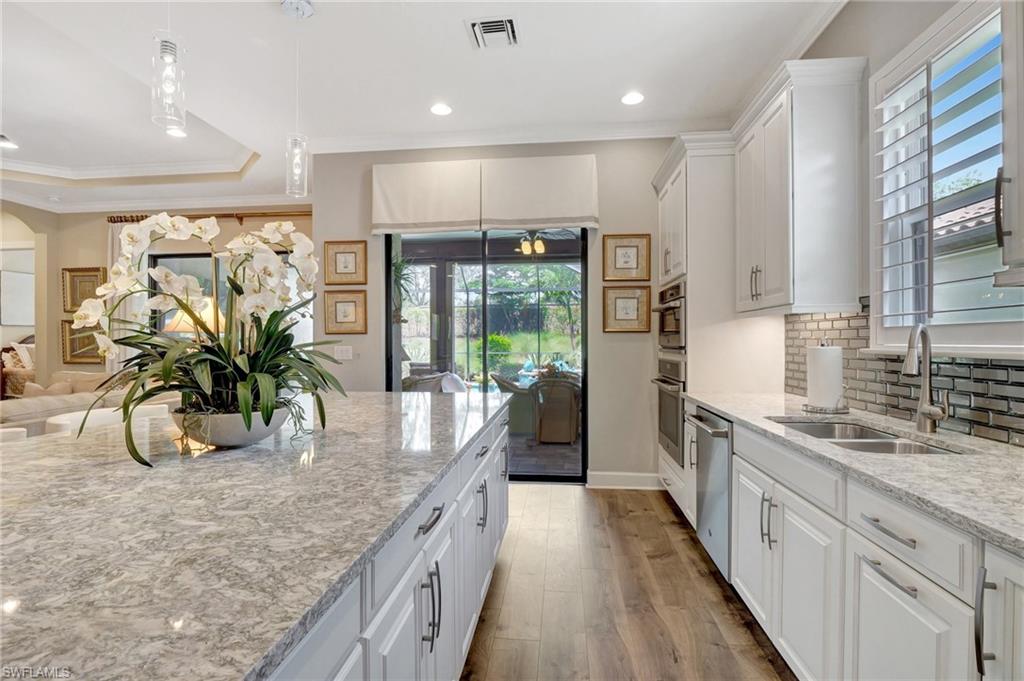 8558 Maggiore Court Naples, FL 34114 - Photo 20 of 50 a kitchen with stainless steel appliances granite countertop sink a refrigerator and wooden floor