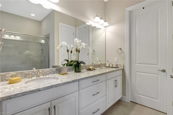 a en suite bathroom with a granite countertop sink a mirror and a shower