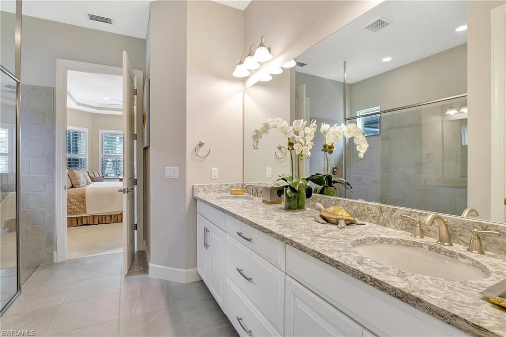 8558 Maggiore Court Naples, FL 34114 - Photo 26 of 50 a en suite bathroom with a granite countertop sink a mirror and a shower