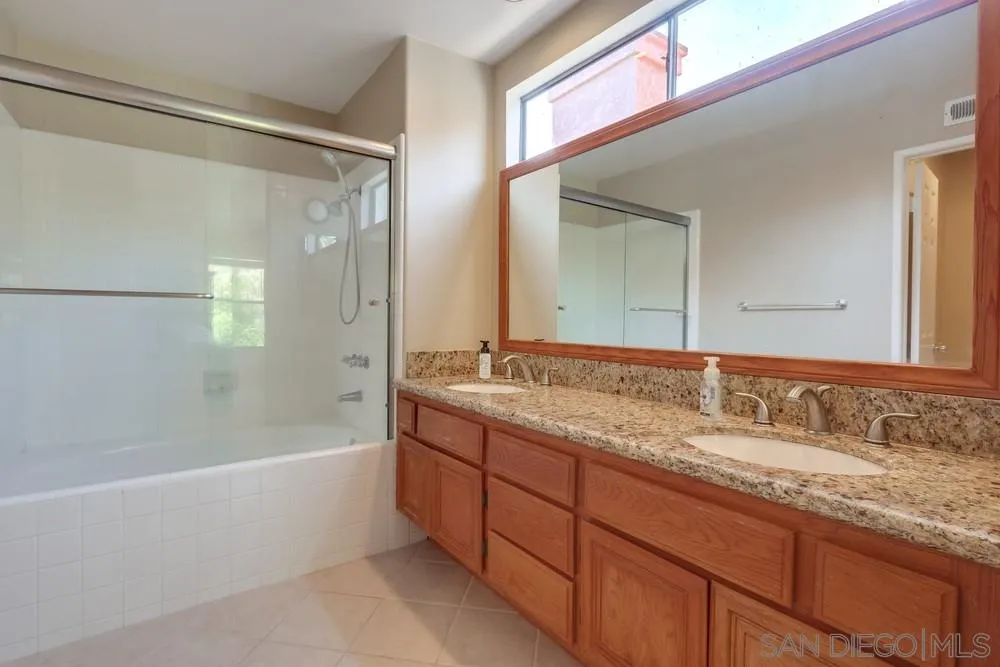 11746 Springside Road San Diego, CA 92128 - Photo 17 of 25 a bathroom with a granite countertop sink mirror and a bath tub