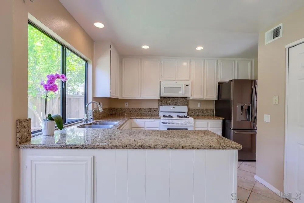 11746 Springside Road San Diego, CA 92128 - Photo 9 of 25 a kitchen with kitchen island granite countertop stainless steel appliances a sink and a refrigerator