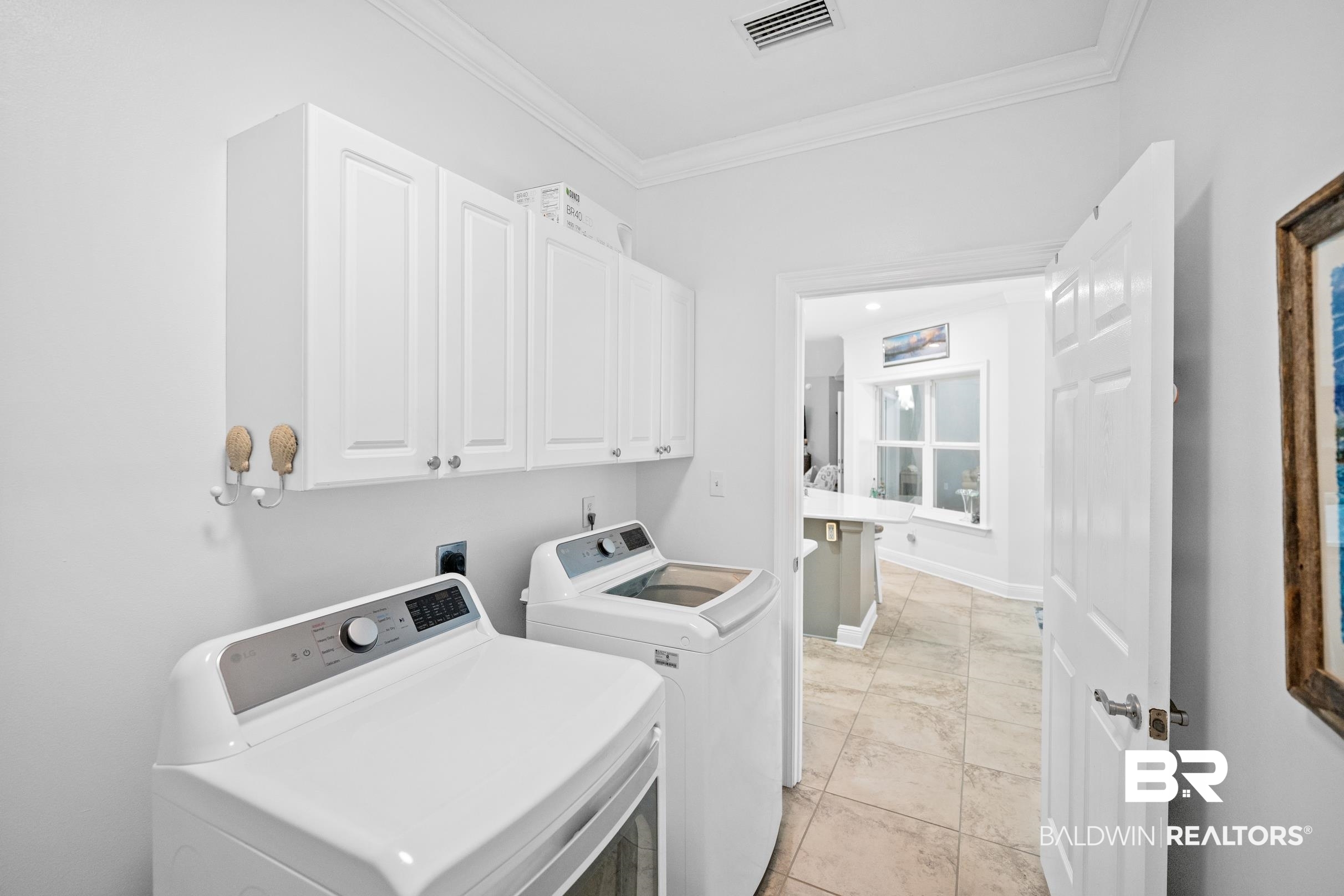 5217 Greentree Road Orange Beach, AL 36561 - Photo 35 of 58 Washroom with cabinet space, washer and dryer, crown molding, and light marble finish flooring