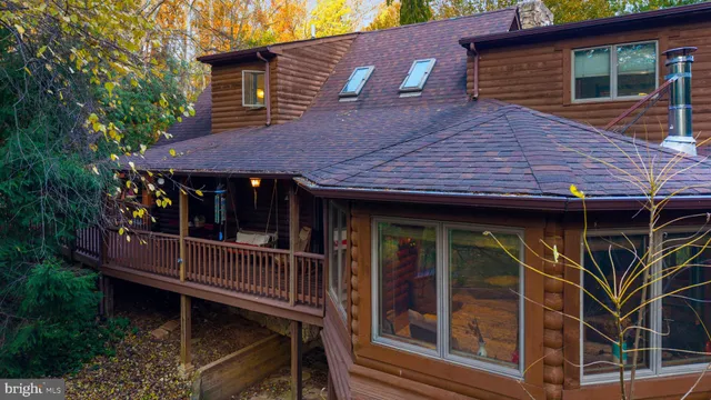 a view of house with wooden deck and floor to ceiling window