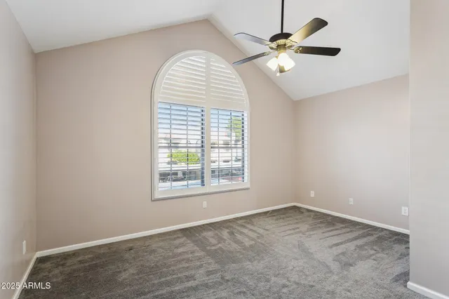 an empty room with chandelier fan and windows