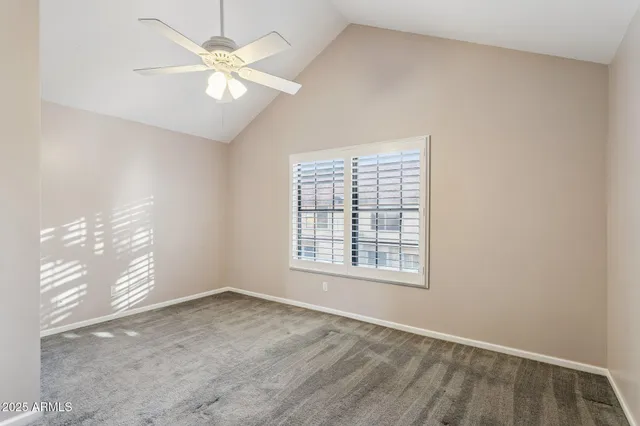 an empty room with chandelier fan and windows