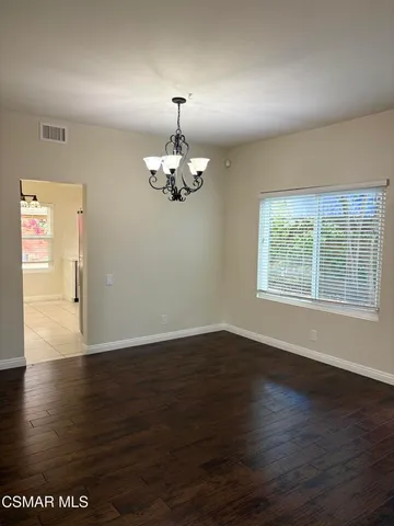 a view of an empty room with window and chandelier fan