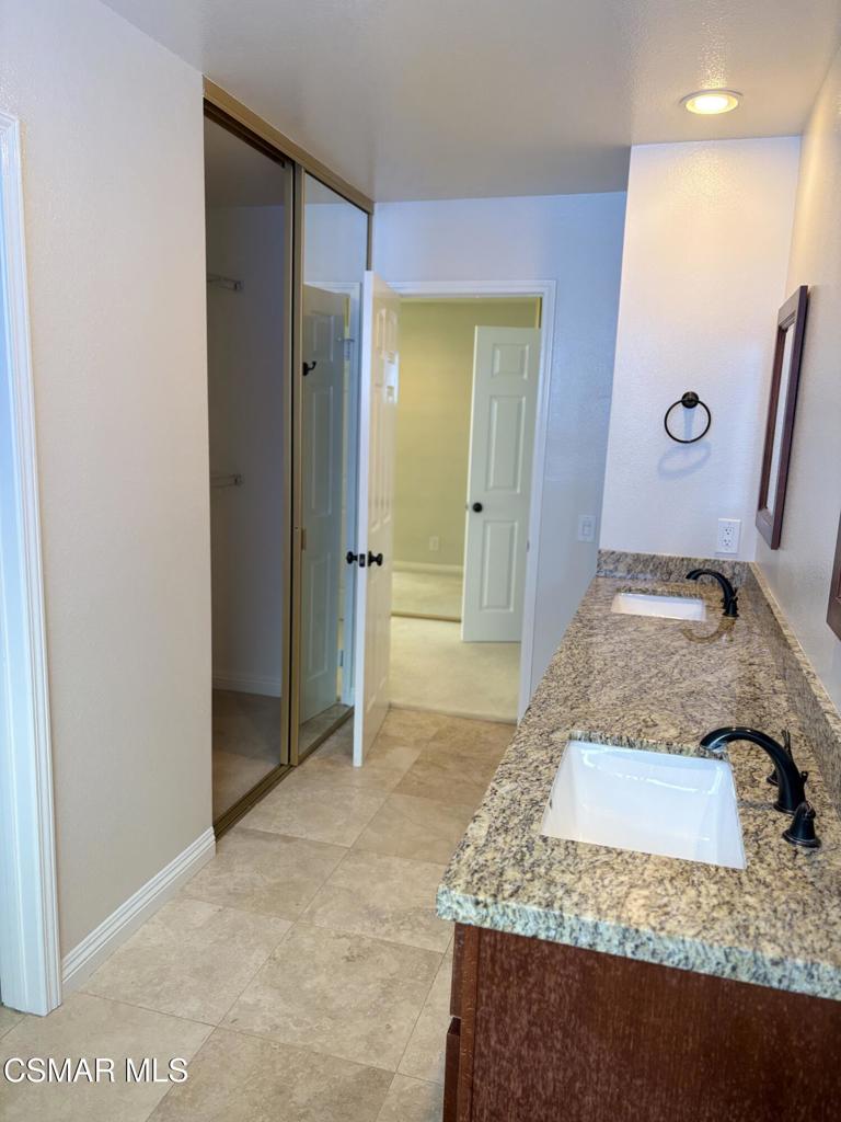 12015 River Grove Court Moorpark, CA 93021 - Photo 23 of 33 a bathroom with a granite countertop sink a mirror and shower