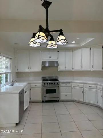 an empty room with wooden floor chandelier and windows