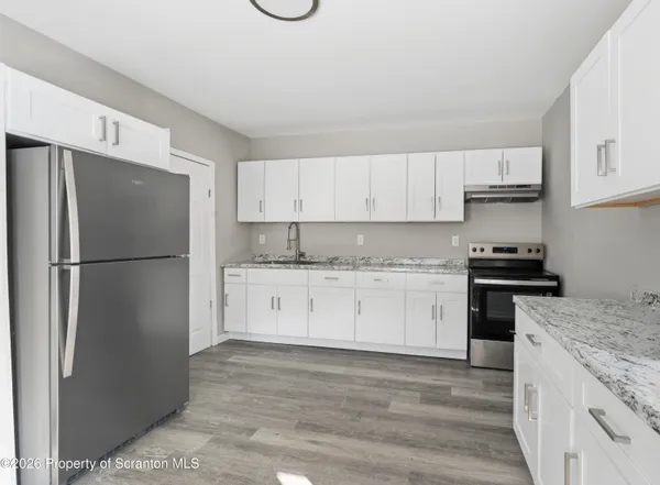 a kitchen with granite countertop a refrigerator stove top oven and cabinets