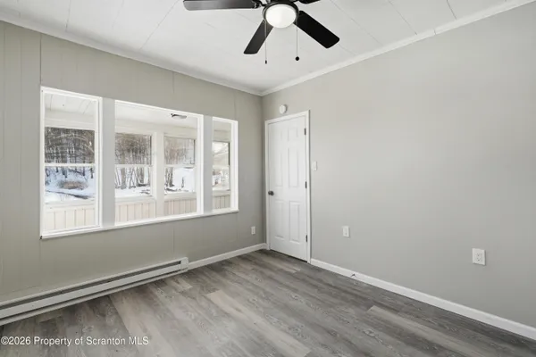 an empty room with wooden floor and windows