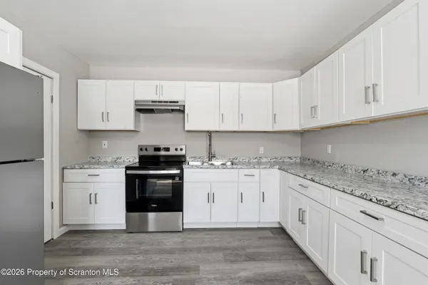 a kitchen with granite countertop white cabinets and stainless steel appliances