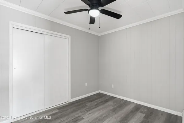 an empty room with ceiling fan and wooden floor