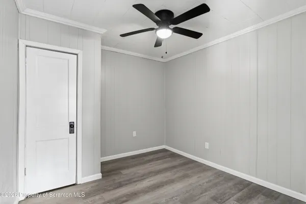 an empty room with wooden floor and a ceiling fan