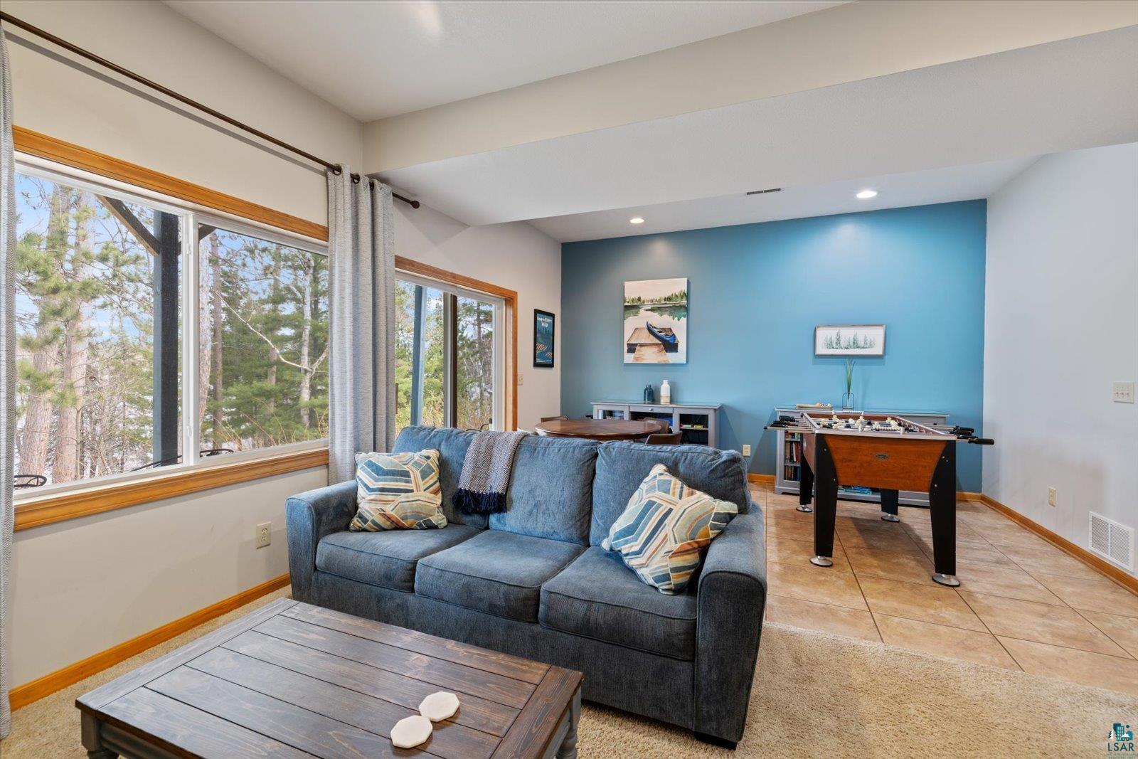 6266 Giants Ridge Road Biwabik, MN 55705 - Photo 14 of 37 Spacious recreation area featuring large windows with natural wood trim, recessed lighting, a distinct accent wall, and a blend of carpet and tile flooring