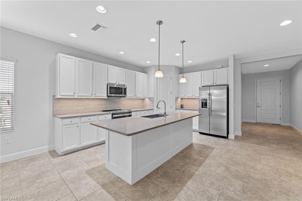 3711 Canopy Circle Naples, FL 34120 - Photo 5 of 28 a kitchen with stainless steel appliances kitchen island a sink dishwasher a refrigerator and white cabinets with wooden floor