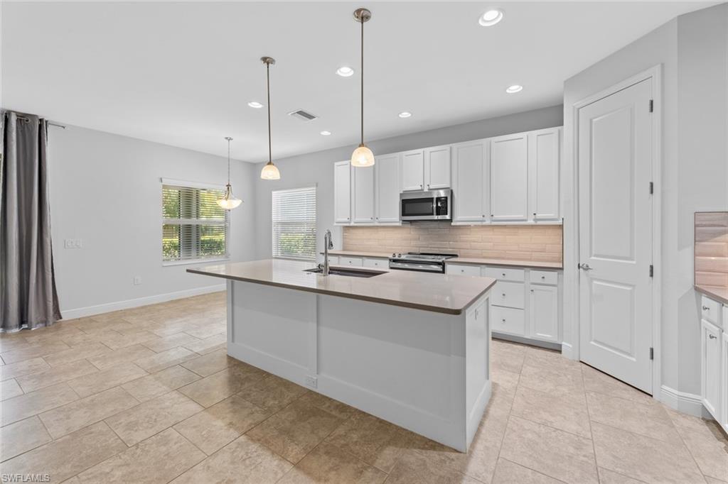 3711 Canopy Circle Naples, FL 34120 - Photo 7 of 28 a kitchen with kitchen island granite countertop a stove a sink a center island a refrigerator and a window