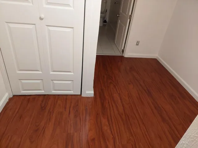 an empty room with wooden floor and cabinet