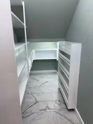 a view of walk in closet with empty racks