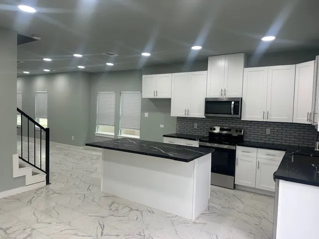 a kitchen with stainless steel appliances granite countertop a stove a sink and a microwave