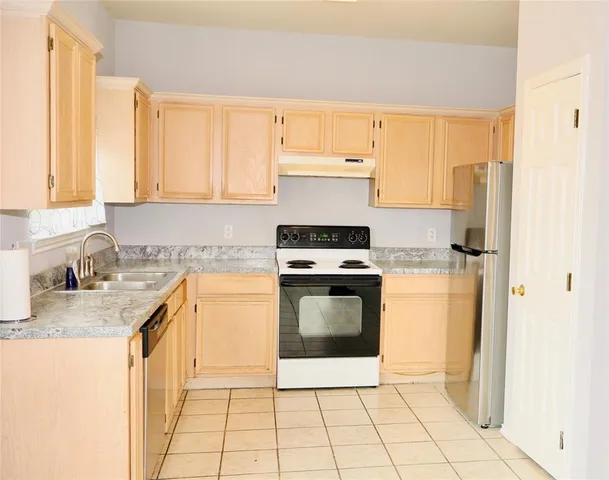 a kitchen with stainless steel appliances granite countertop a stove a sink and a refrigerator