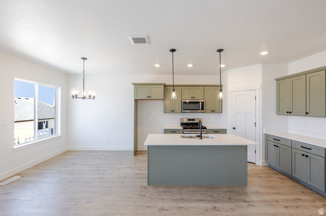 4752 Heartwood Road, Unit 433 Mapleton, UT 84664 - Photo 3 of 20 Kitchen featuring hanging lights, stainless steel appliances, light wood-style floors, and an island with sink