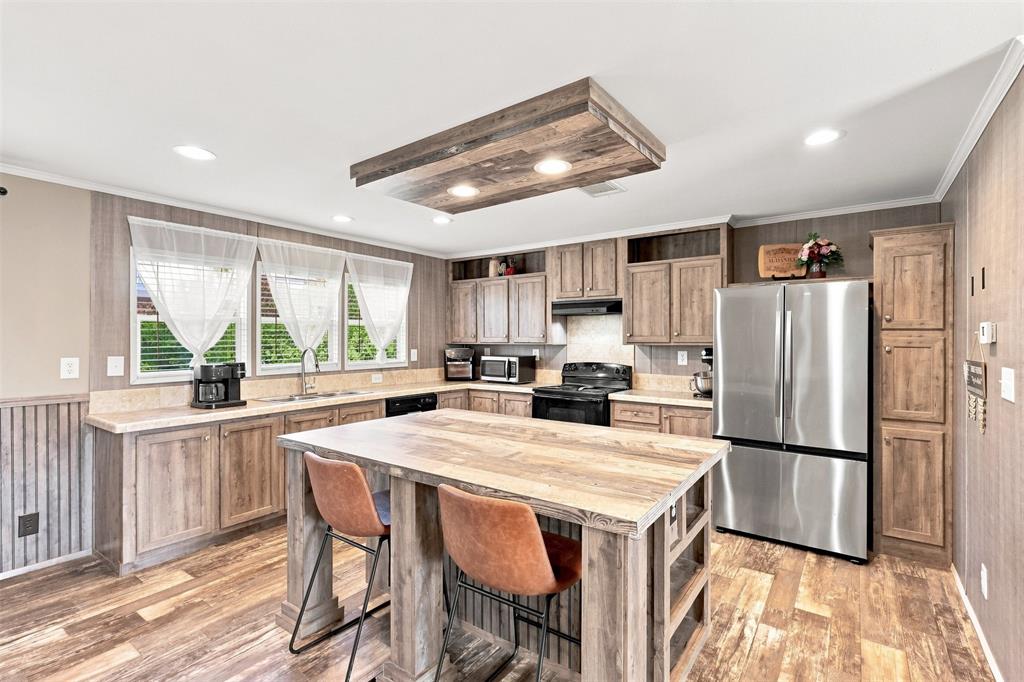 Kitchen featuring a central island, stainless steel refrigerator, built-in cabinetry, recessed lighting, and wood-finish flooring