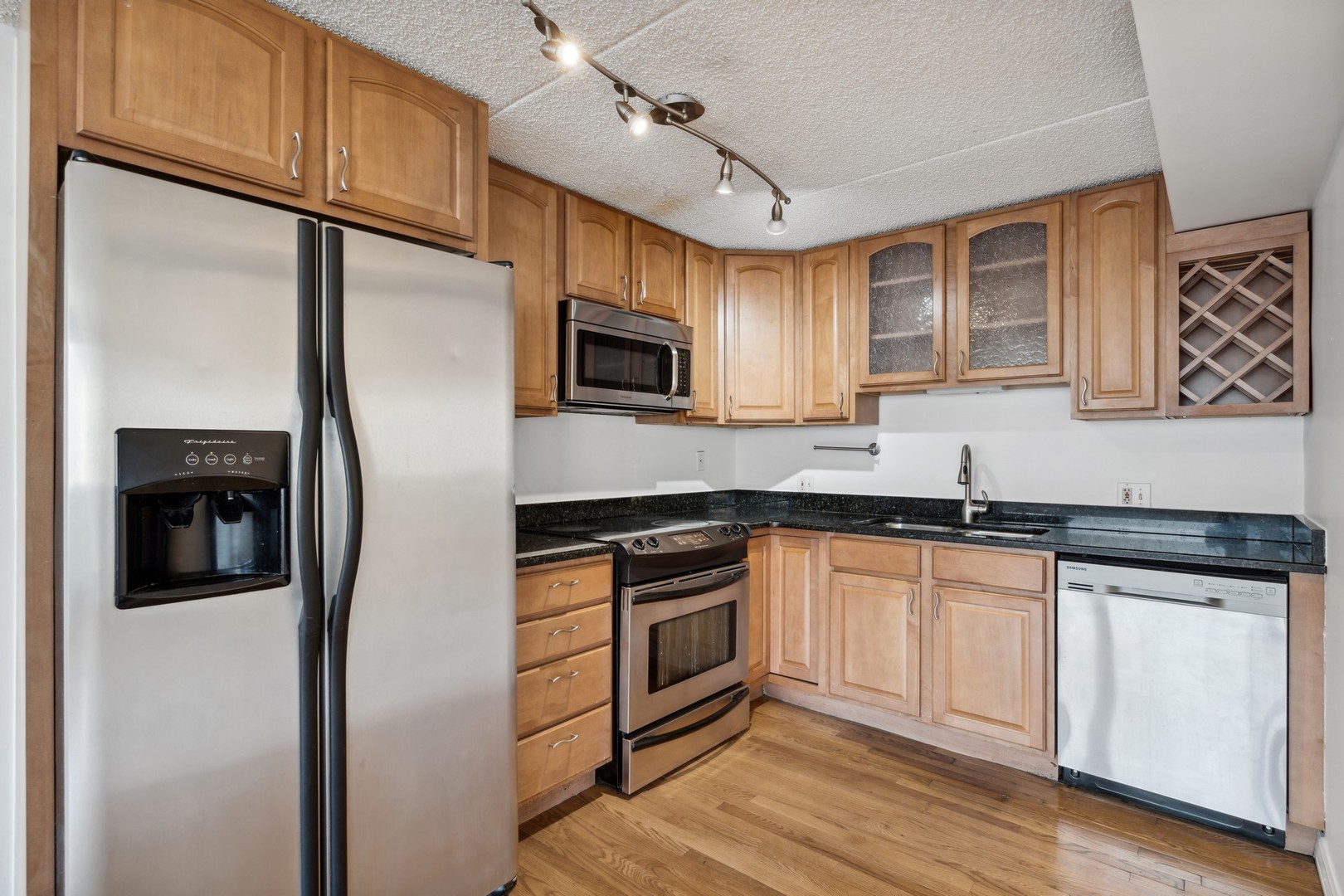 4900 North Lester Avenue, Unit 5 Chicago, IL 60630 - Photo 7 of 18 a kitchen with granite countertop a refrigerator a microwave a sink and dishwasher with wooden floor