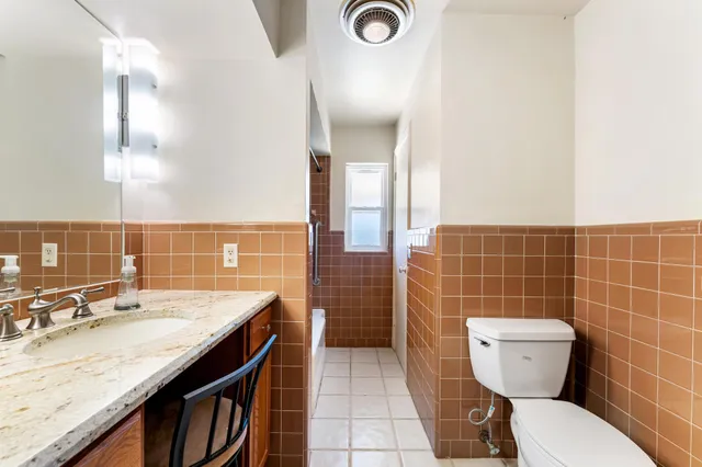 a bathroom with a granite countertop toilet sink and mirror