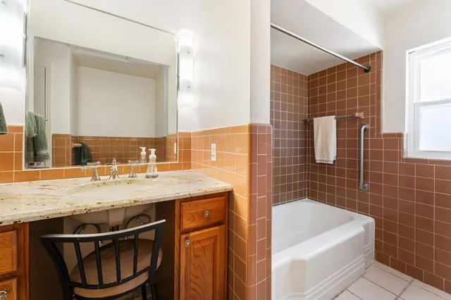 a bathroom with a granite countertop sink a mirror and bathtub