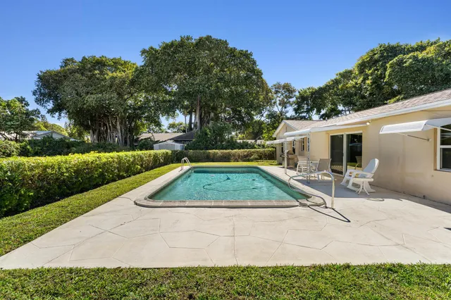a view of backyard with swimming pool and seating space