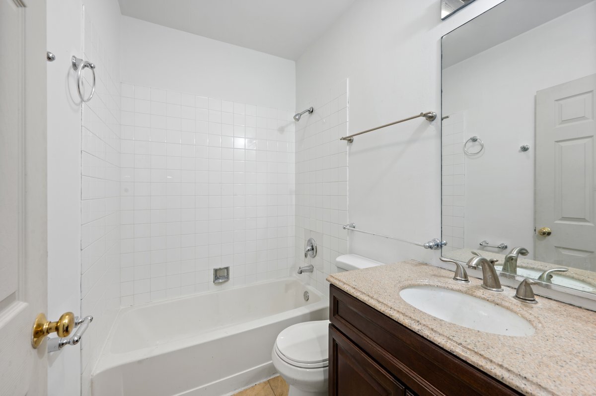 1412 West Diversey Parkway, Unit B Chicago, IL 60614 - Photo 19 of 26 a bathroom with a granite countertop sink a toilet a mirror a bathtub and shower