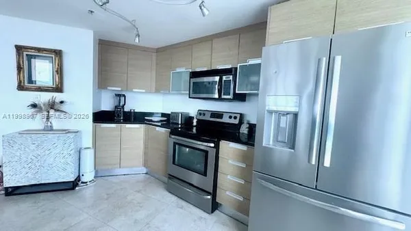 a kitchen with stainless steel appliances granite countertop a refrigerator a stove a sink and a microwave