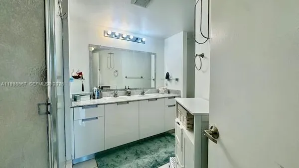 a bathroom with a double vanity sink mirror and shower