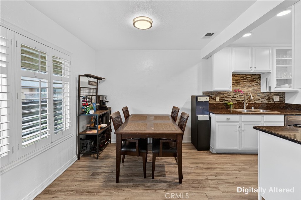 1430 West Lambert Road, Unit 384 La Habra, CA 90631 - Photo 12 of 41 a kitchen with stainless steel appliances kitchen island granite countertop a table chairs in it and wooden floors