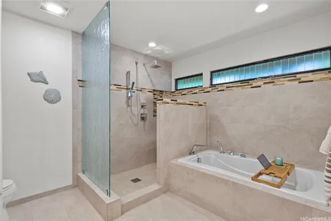 a bathroom with a tub a mirror and shower