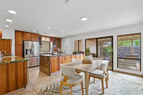 a dining room with stainless steel appliances granite countertop a refrigerator a stove a dining table and chairs with wooden floor