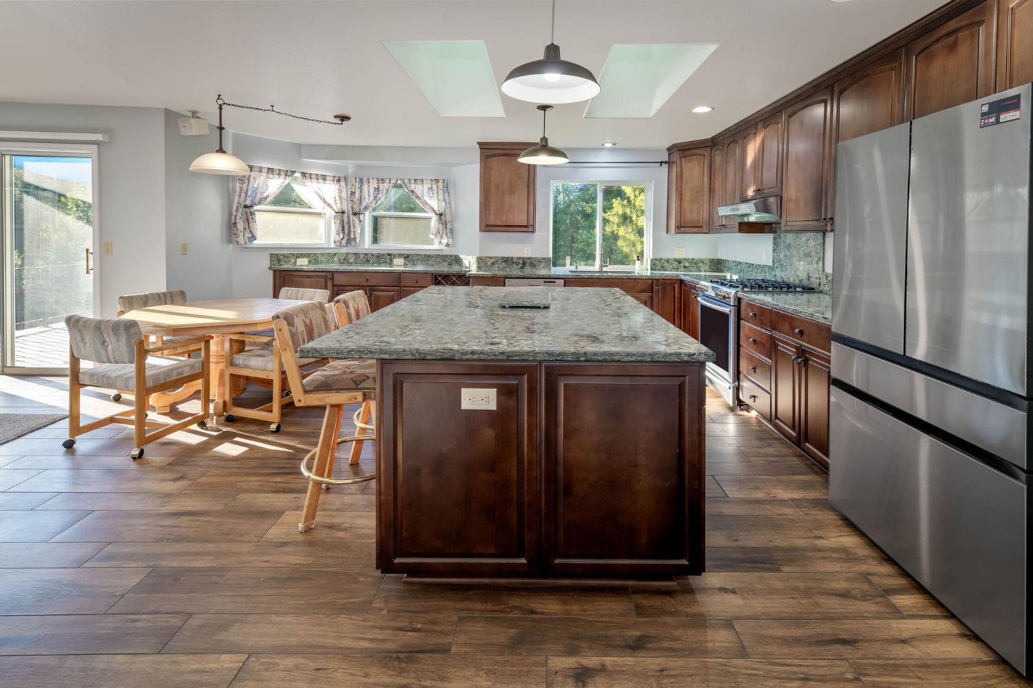 12401 Old Mine Road Grass Valley, CA 95945 - Photo 39 of 87 a kitchen with kitchen island granite countertop wooden cabinets and a refrigerator