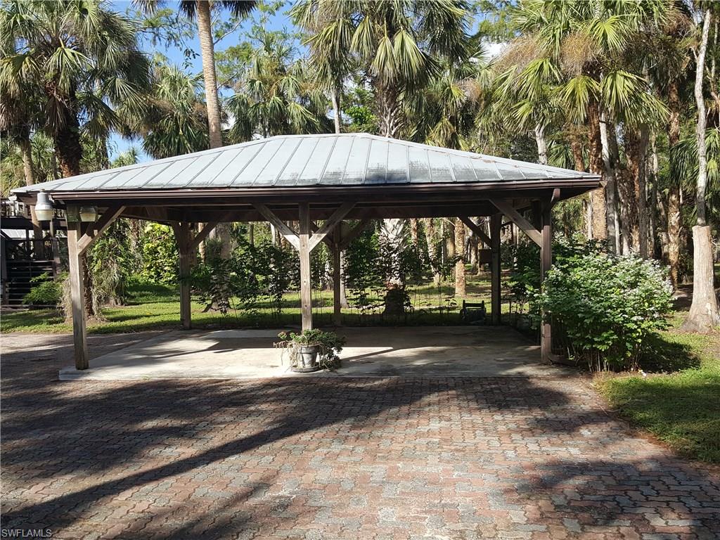 2221 Krape Road Naples, FL 34120 - Photo 3 of 24 a view of a patio with table and chairs under an umbrella with large trees