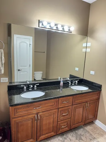 a bathroom with a granite countertop double vanity and a mirror
