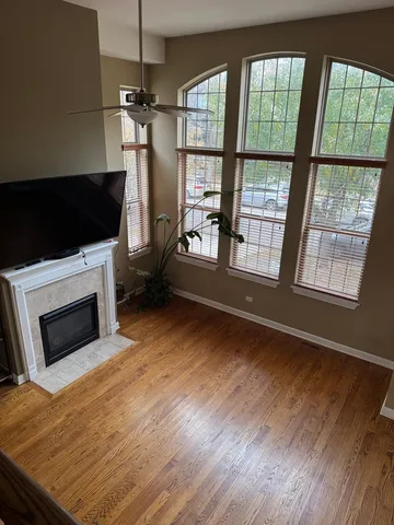 a living room with a fireplace furniture a ceiling fan and a large window