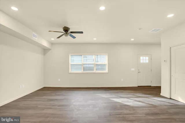 an empty room with ceiling fan and windows