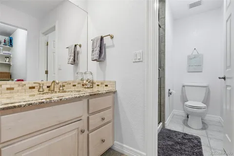 a bathroom with a granite countertop sink a toilet and shower