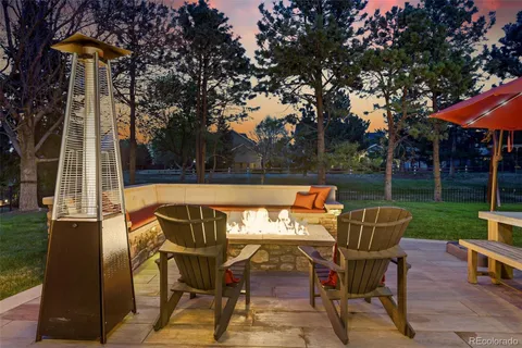 a roof deck with table and chairs and potted plants with wooden floor and fence