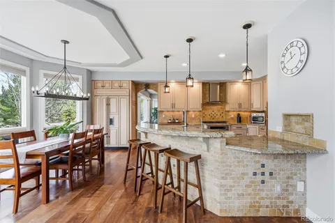 a kitchen with stainless steel appliances white cabinets a sink a stove a wooden floors and a window