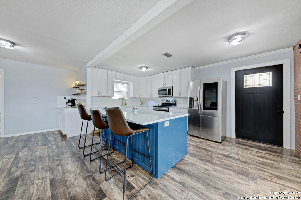 1510 Timmermann Road Seguin, TX 78155 - Photo 7 of 32 a kitchen with stainless steel appliances kitchen island granite countertop a table chairs and a refrigerator