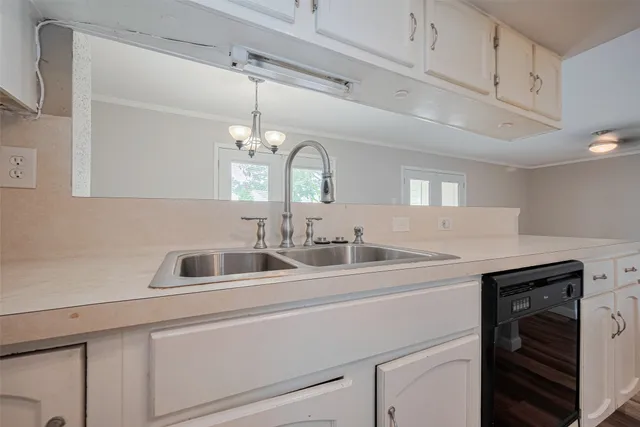a kitchen with a sink dishwasher and white cabinets with wooden floor