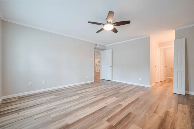 a view of empty room with wooden floor and fan